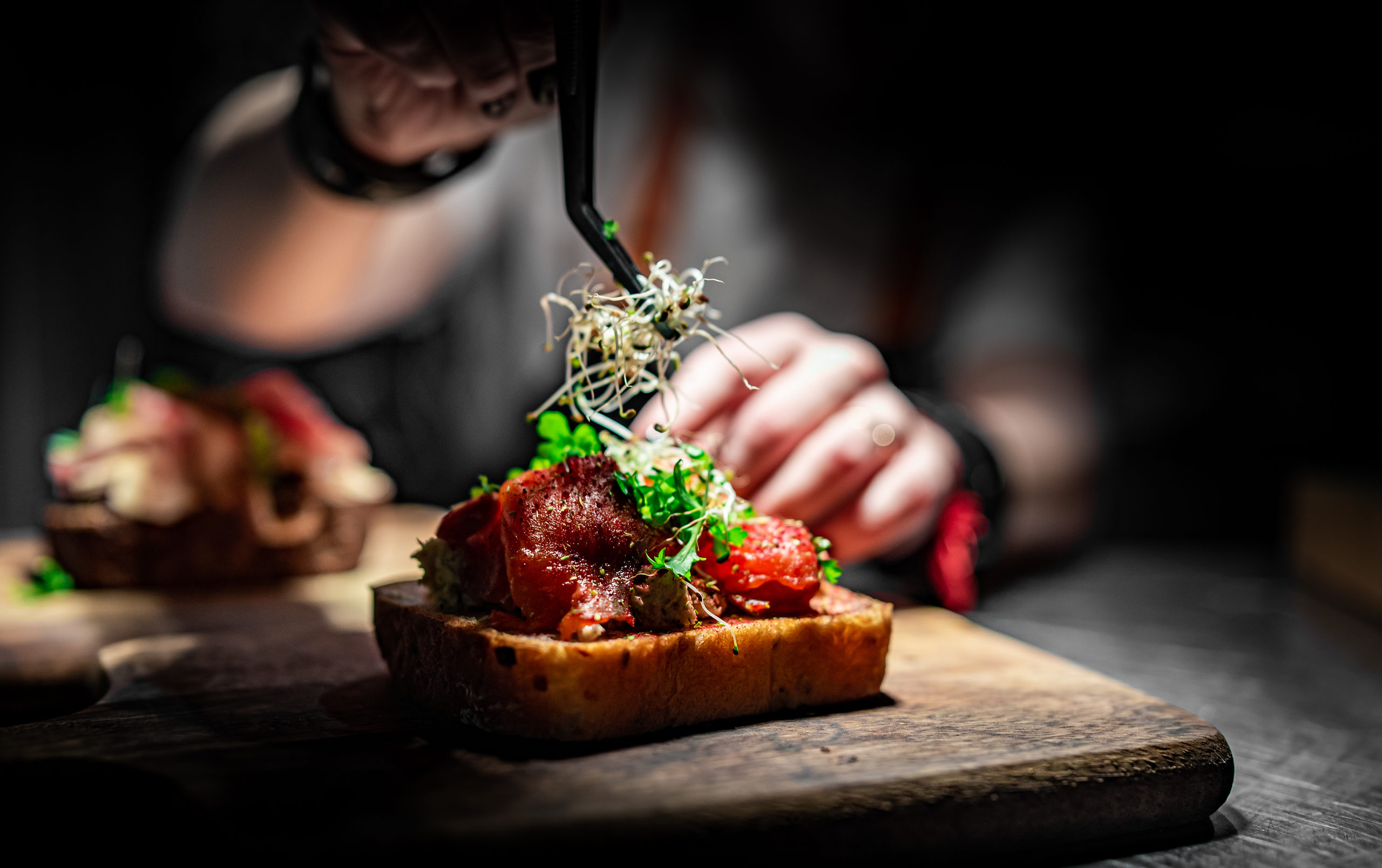 Chef hand decorate food on wooden plate in cafe kitchen